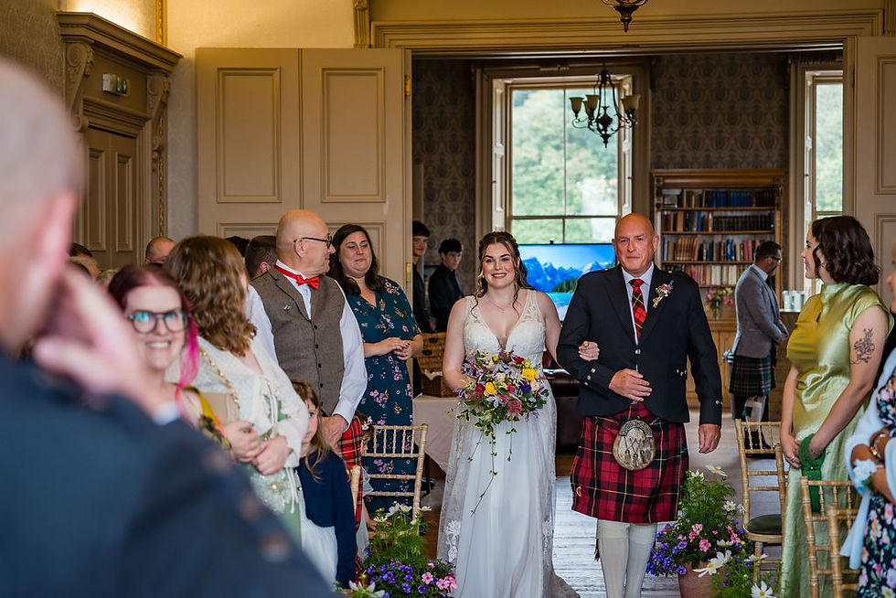 Bride walking down the aisle during an intimate Scottish castle wedding surrounded by family and friends.