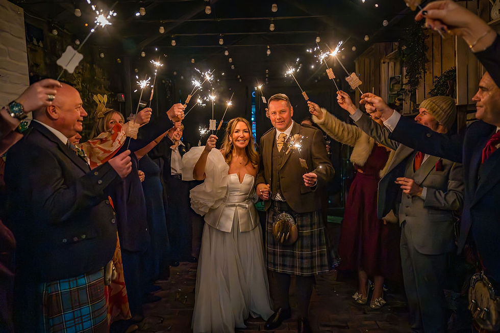 Bride and groom surrounded by guests holding sparklers during their winter wedding at Forgan’s Broughty Ferry.