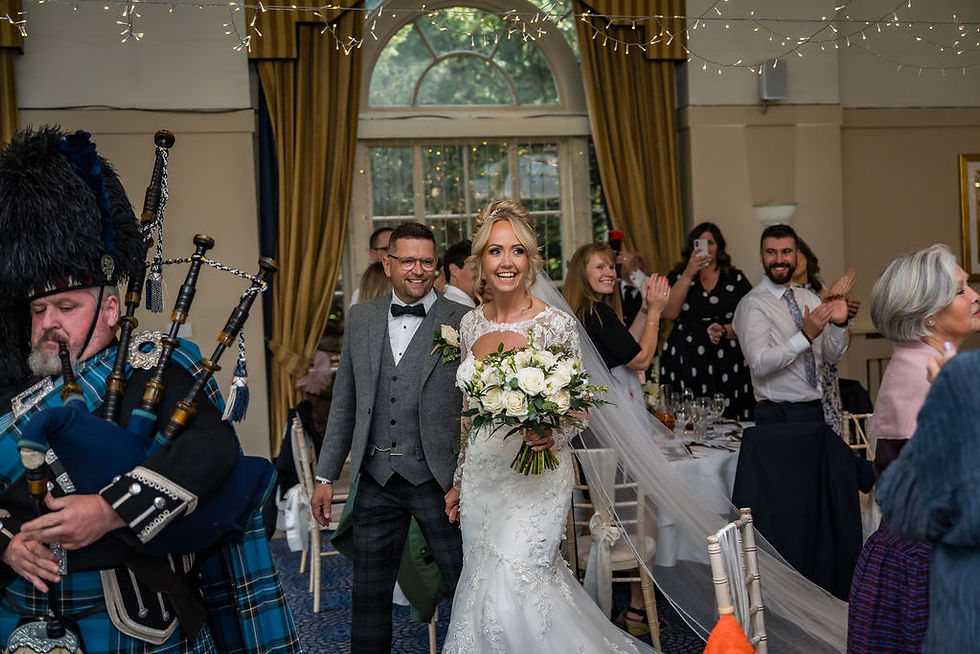 Newlyweds entering reception room led by Scottish piper at Balbirnie House wedding celebration
