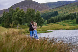 Couple laughing together during a natural pre-wedding photoshoot in Glen Clova, surrounded by beautiful mountain scenery.