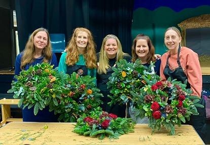 4 ladies proudly showing their handmade wreath with fresh foliage, flowers and berries