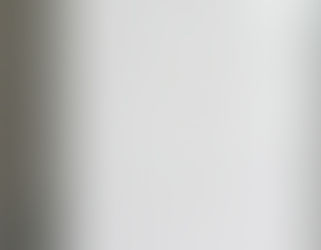 Close-up of a white tiled wall with glossy rectangular tiles. A metal faucet is slightly visible in the background. Bright and clean setting.