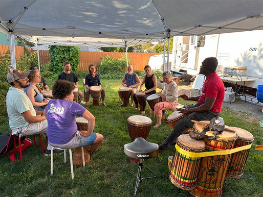 photo of people sitting in drum circle performing Guinean music