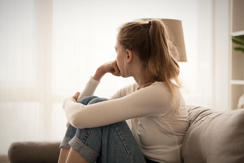 Une femme assise sur un canapé regarde par la fenêtre