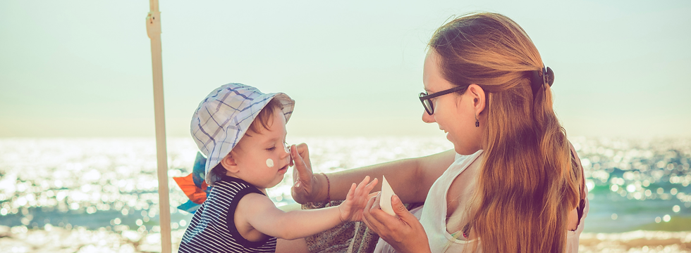Woman applying sunscreen to toddler's face on the beach