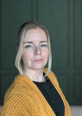 Photo of Hollie with a green background, Hollie has her hair up and has a yellow cardigan and black top