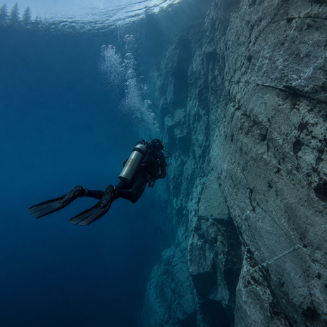 Scuba diver exploring a deep underwater rock wall