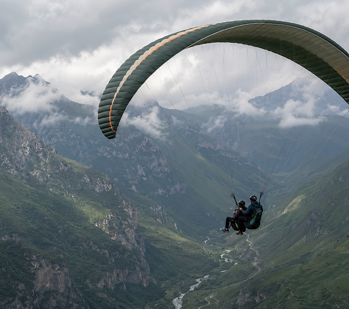 A paraglider flying above a deep mountain valley in the Caucasus