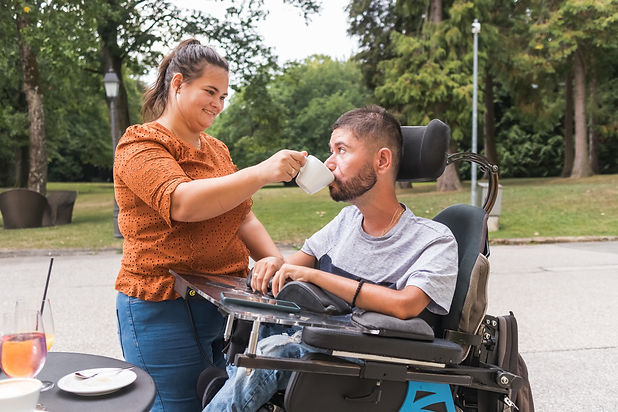 Girlfriend assisting her boyfriend with physical disability drinking coffee in a cafe. Lov