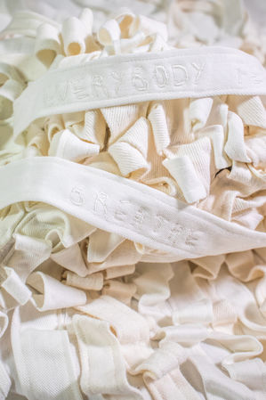 Textile artwork made from white recycled denim strips with digital embroidery of handwritten phrases: "Everything is going to be alright", "Everybody feels this way" and "Breathe and observe".