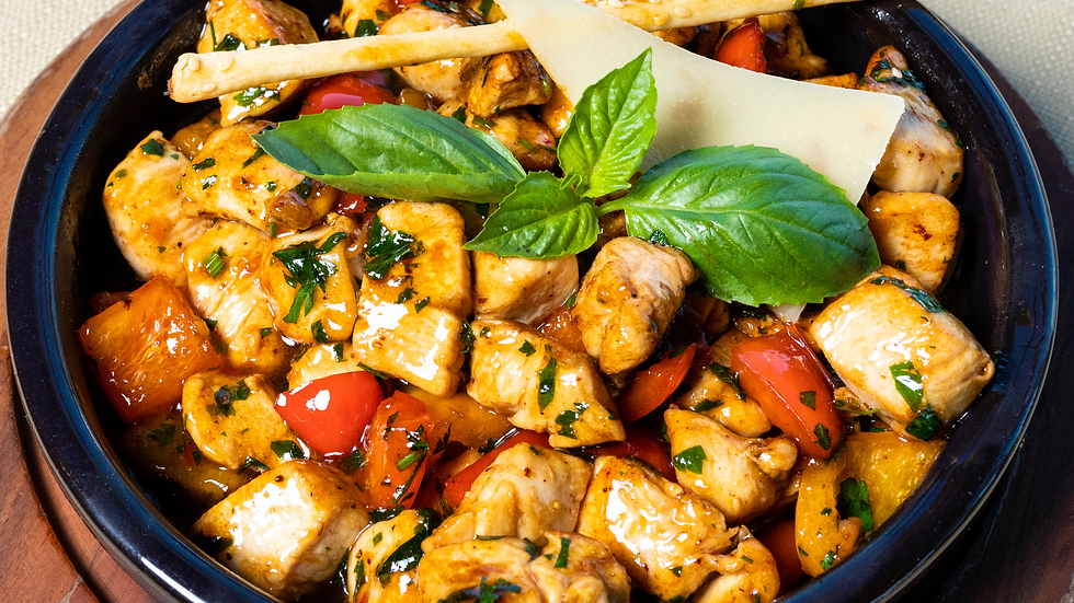 bowl of chicken, tofu, tomotoes, basil, a slice of cheese, a breadstick in a marinade