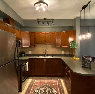 Boho kitchen with cherry cabinets, industrial lighting and an eclectic rug.