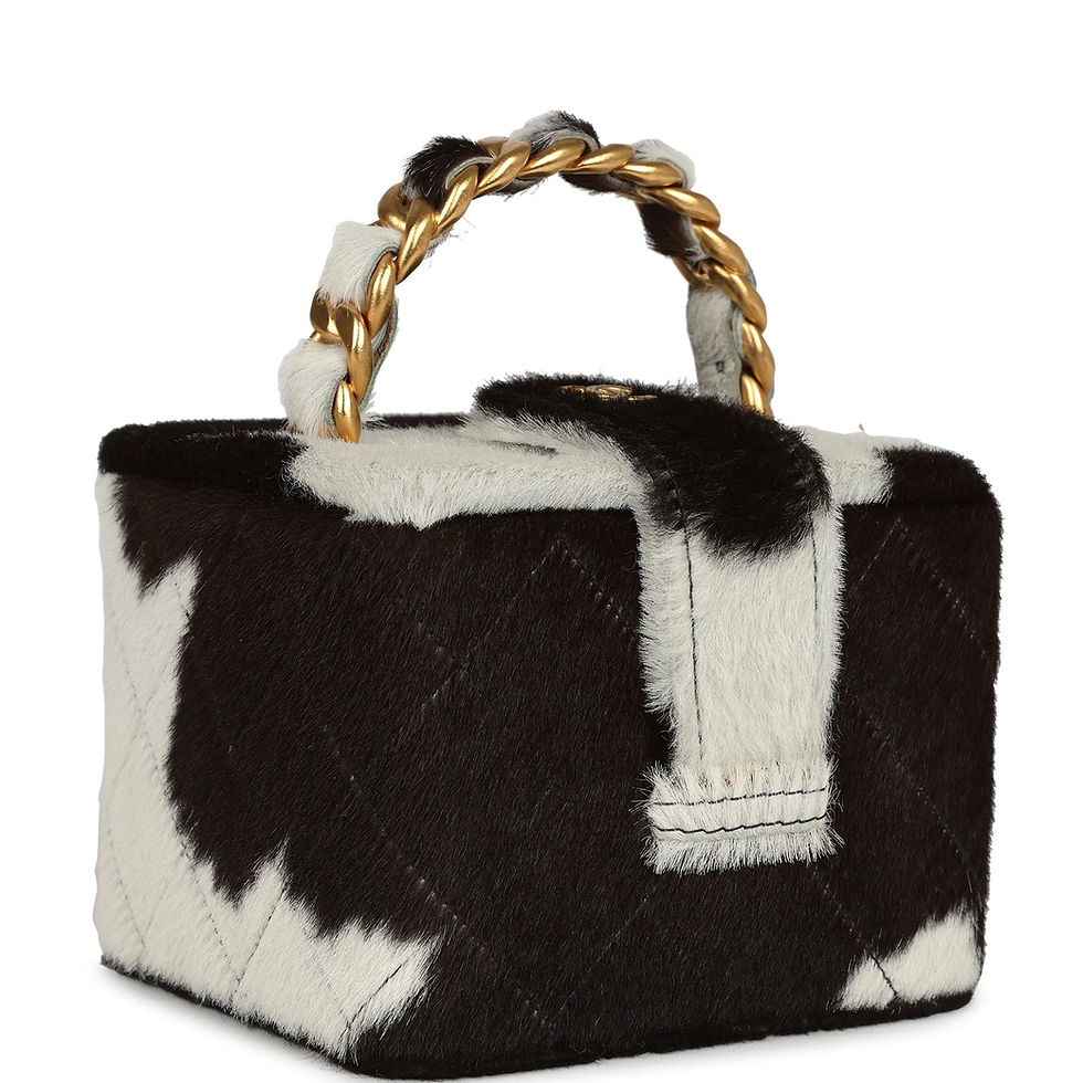 Three-quarter angle showing the cow-print ponyhair panels and chain handle