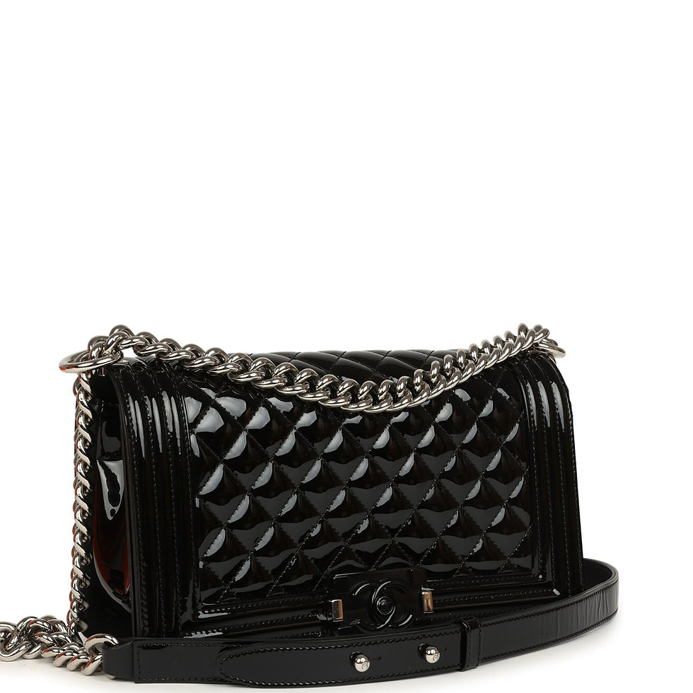 Three-quarter view of the black patent Boy Bag showing the quilted flap and CC push-lock clasp