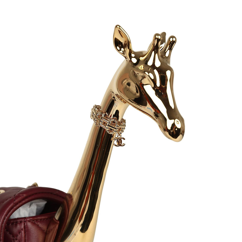 Thumbnail: Close-up of the display stand's gold-tone chain collar and CC charm beside the burgundy flap