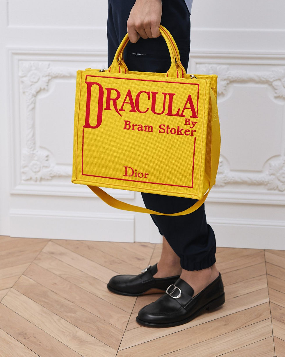 Dior Medium Book Tote in yellow embroidered canvas with Dracula cover – carried by hand by model