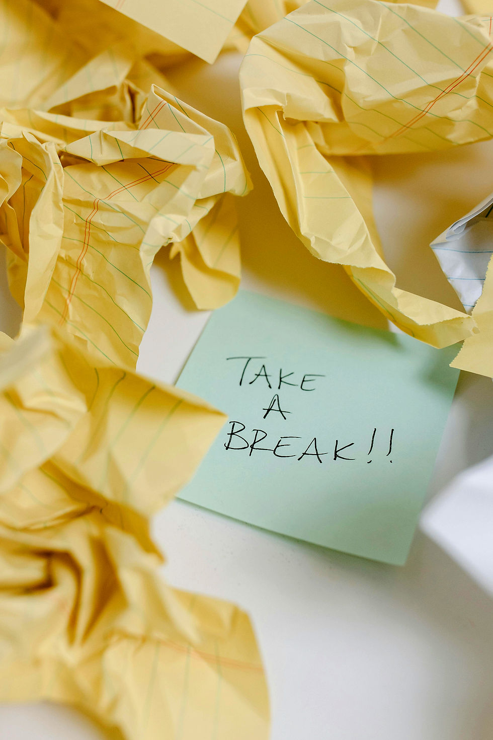 Crumpled yellow paper surrounding a blue sticky note reading "TAKE A BREAK!!"