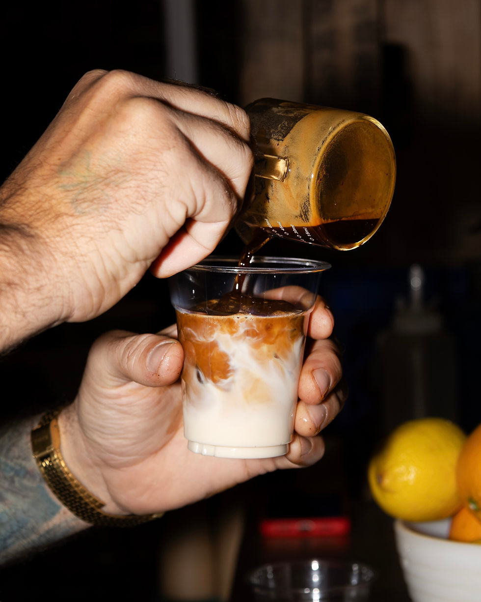 Close-up view of a barista pouring steamed milk into a ceramic cup at a festival table.