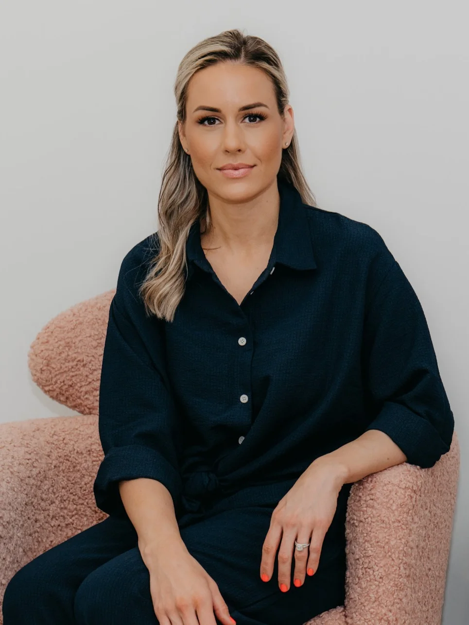 Ashley Cammisuli headshot - owner of GLOW Beauty Bar sitting in a chair