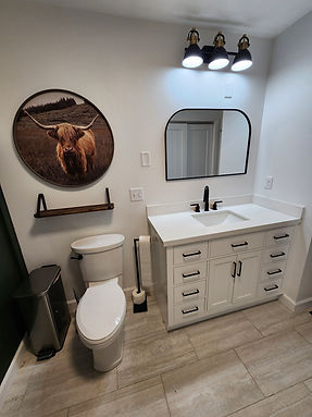 A finished bathroom remodel project that has a cute photo of  a cow on the wall.