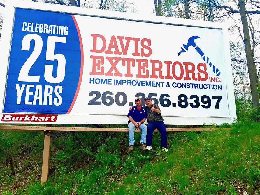 John Davis sitting on a billboard for Davis Exteriors celebrating 25 years.