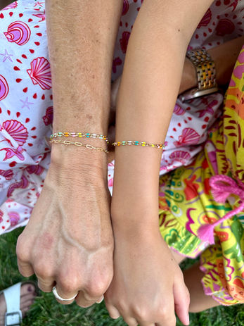 Multiple women's hands joined together to showcase their permanent jewelry.