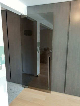 Pivoterende en zelfsluitende glazen deur in brons getint glas in landelijke woning.