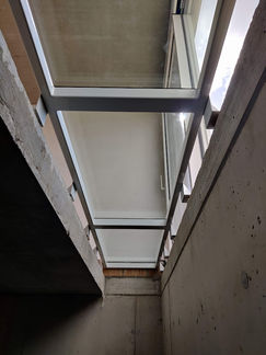 Glazen vloer in wit gelakte stalen kader met drie glaspanelen, ontworpen om natuurlijk licht in de kelder binnen te laten.