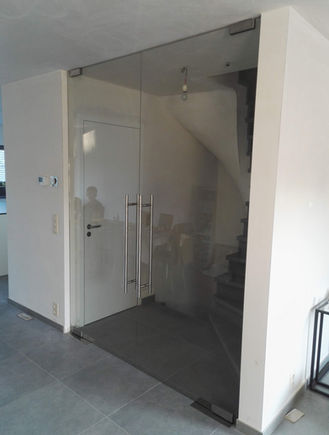 Dubbele pivoterende en zelfsluitende glazen deur in helder glas in landelijke woning.