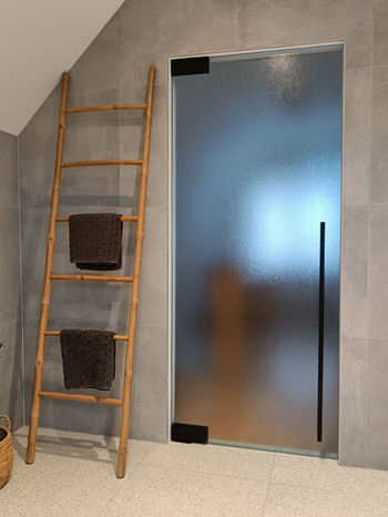 Pivoterende en zelfsluitende glazen deur in Crepi figuurglas in moderne badkamer.