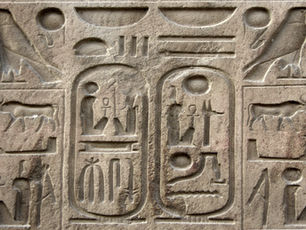 Ancient Egyptian stone relief with hieroglyphs, featuring animals and symbols, carved into tan stone. No visible text or color.