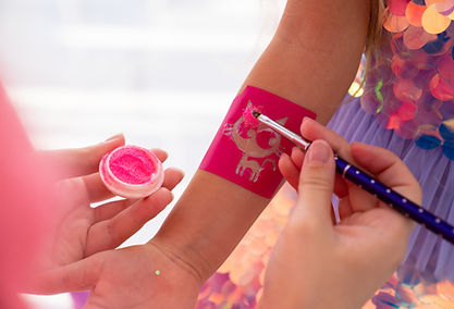 the child makes a temporary tattoo of a kitten with pink sequins decorative cosmetics for