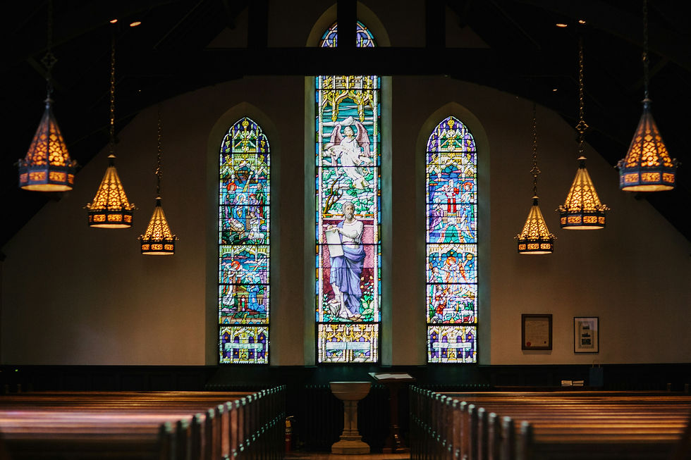 Church interior with colorful stained glass windows, ornate hanging lamps, wooden pews, and a serene atmosphere.