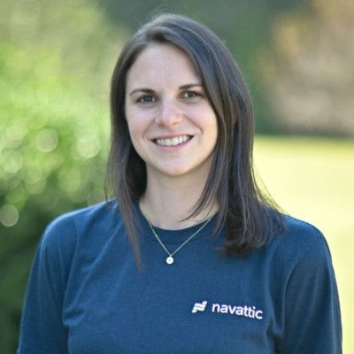 Smiling woman outdoors in a navy Navattic shirt, with a blurred green background and a friendly, relaxed expression.