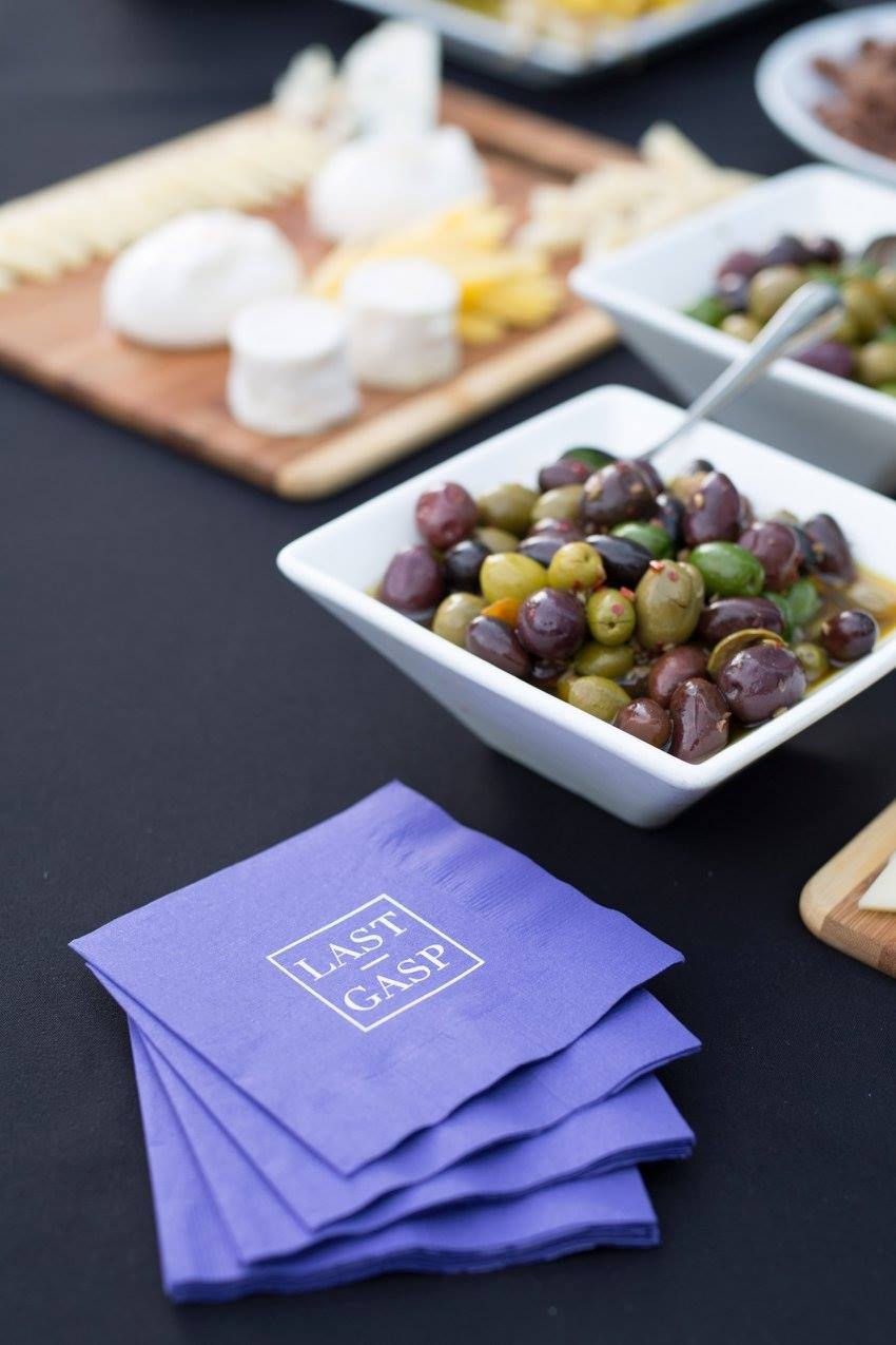 Bowl of gourmet olives and branded napkins on a catering table at the Last Gasp rooftop event.