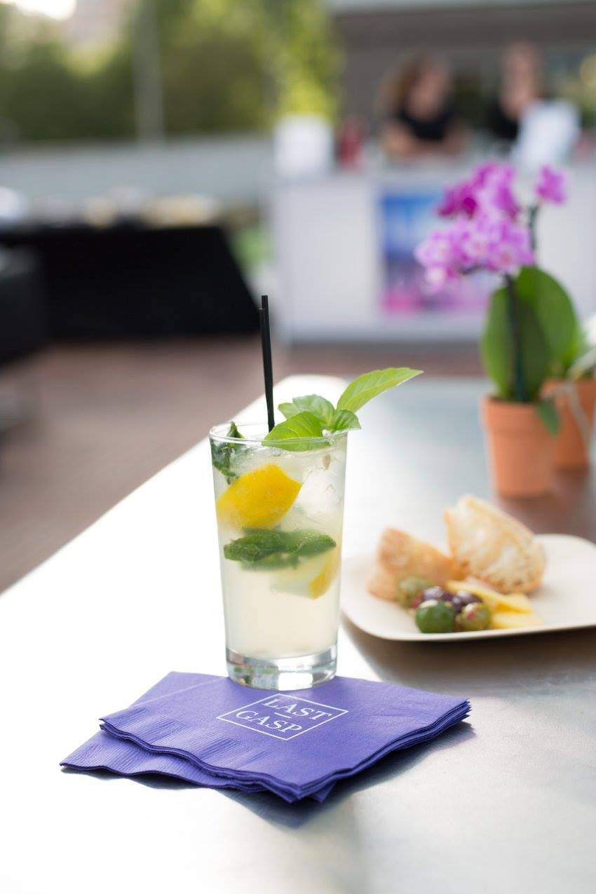 Close-up of mint cocktail and custom branded purple napkins at a summer rooftop event.