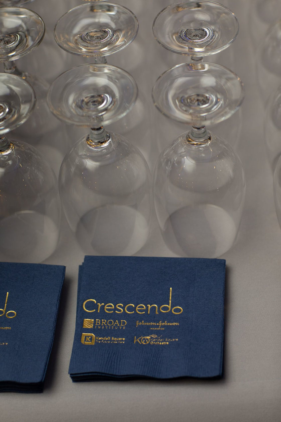 Close-up of Crescendo-branded napkins and stacked wine glasses on the bar.