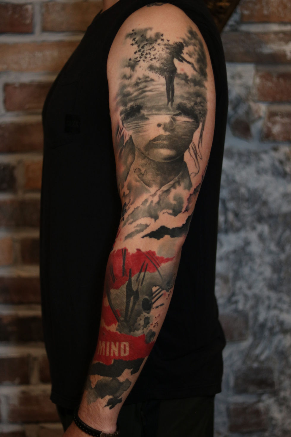 Abstract realism full sleeve tattoo featuring a surreal portrait, landscape, figure dissolving into birds, and red and black abstract elements by Vancouver tattoo artist Michi.