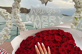 Engagement ring on red roses, 'Will You Marry Me?' sign
