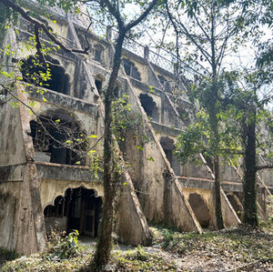 Abandoned structure with arched windows surrounded by trees, Rishikesh 2024, India.