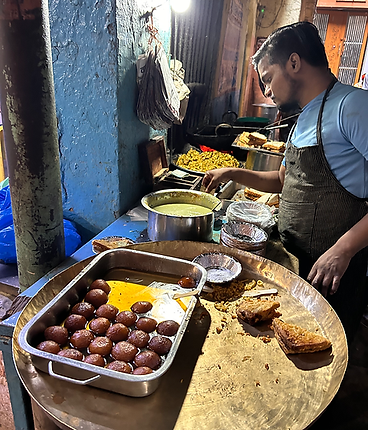 Man cooking Indian sweets and snacks at a street food stall.