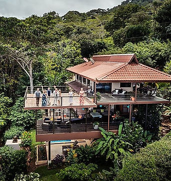 Luxury villa surrounded by lush greenery in Costa Rica, with people on balcony.
