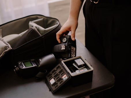 Photographer picking up camera from table surround by photography gear and natural light