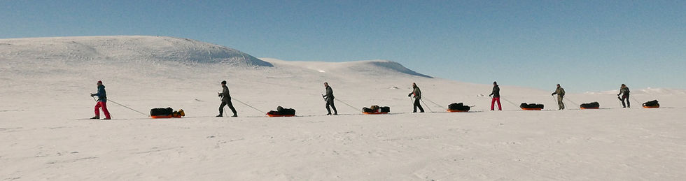 People hiking in the snow behind a leader