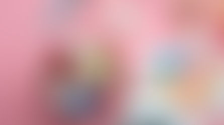 Open pill bottle with assorted capsules and tablets spilling onto a pink background.