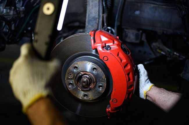 Partial view of repairman in gloves holding lamp near car disc brake in garage_.jpg