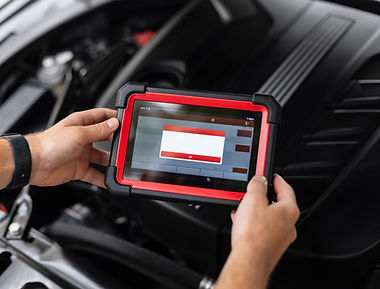 Close-up of a technician holding an advanced diagnostic device inside a car, performing sy