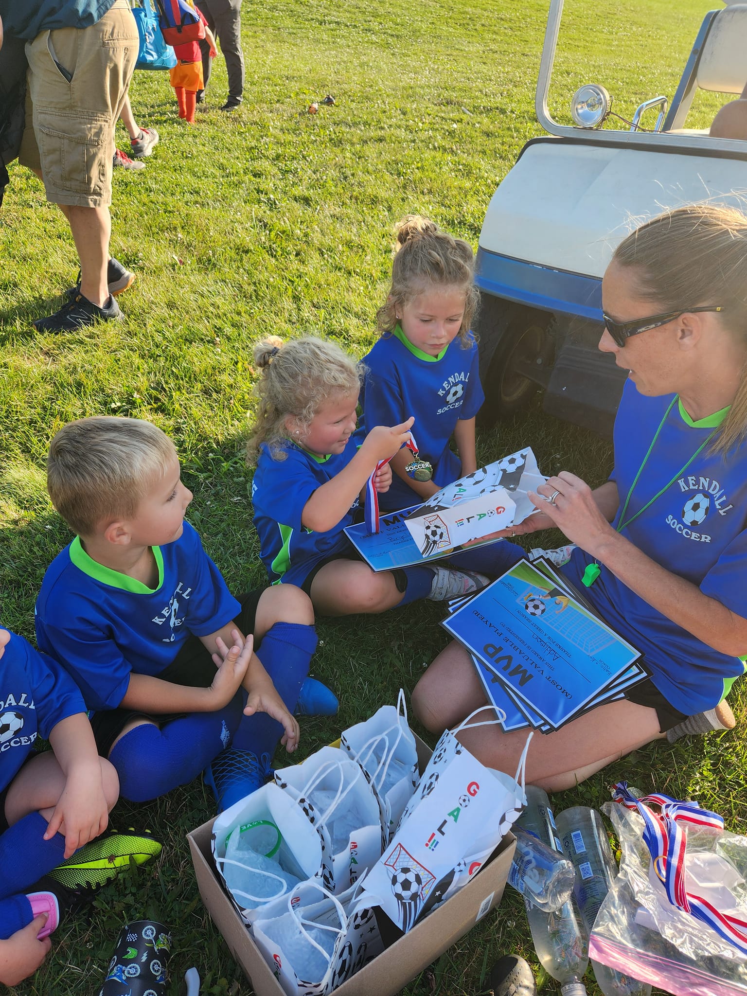 Young soccer players receiving awards and certificates from a coach on a field