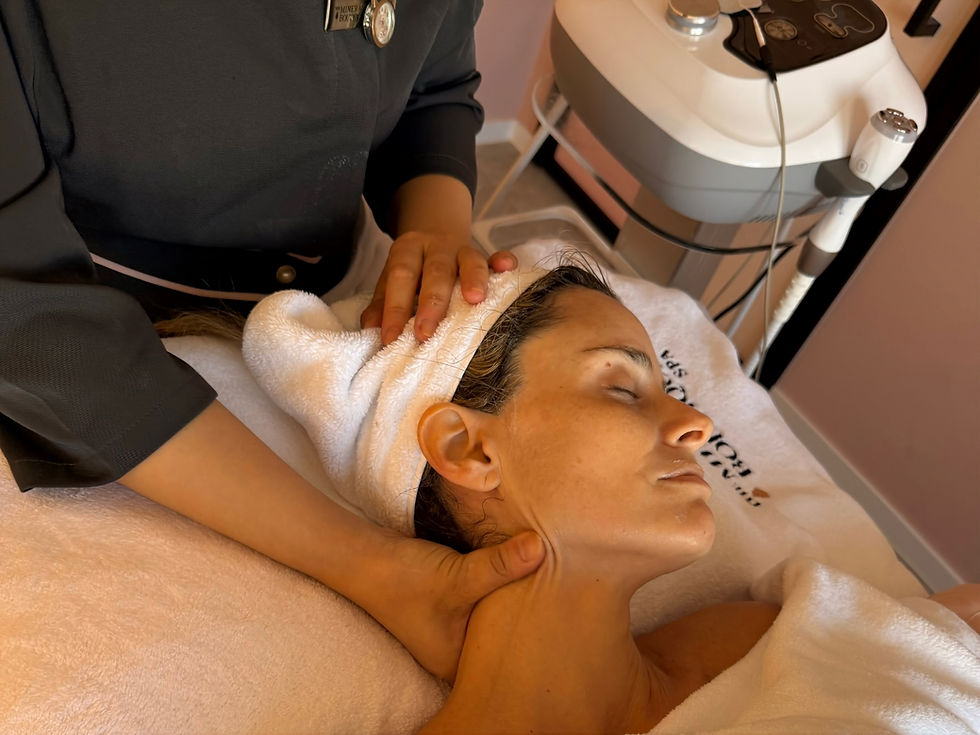 Spa facial massage: therapist gently holds a woman’s head with a towel wrap beside a skincare machine in a calm treatment room