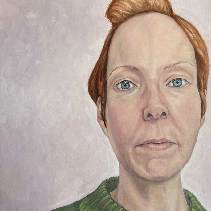 head and shoulders portrait of a women staring at the viewer. She has short red hair and a green jumper.